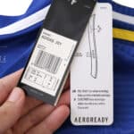 Close-up of Leeds United 2025/26 Away Fan Version jersey tags showing size, product info, and AEROREADY label.
