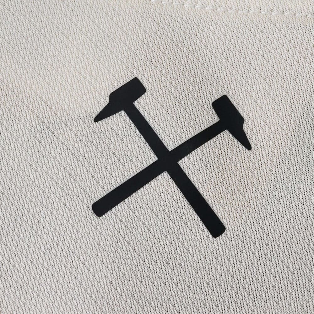 Close-up of black crossed hammers logo on the West Ham United Away 2025/26 Fan Version jersey fabric.