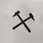 Close-up of black crossed hammers logo on the West Ham United Away 2025/26 Fan Version jersey fabric.