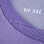 Close-up of the collar on the Brighton & Hove Albion 2025/26 away fan jersey in purple with “WE ARE” text inside.
