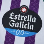 Close-up of the Estrella Galicia 0.0% sponsor logo on the Real Valladolid 2025/26 home fan jersey.