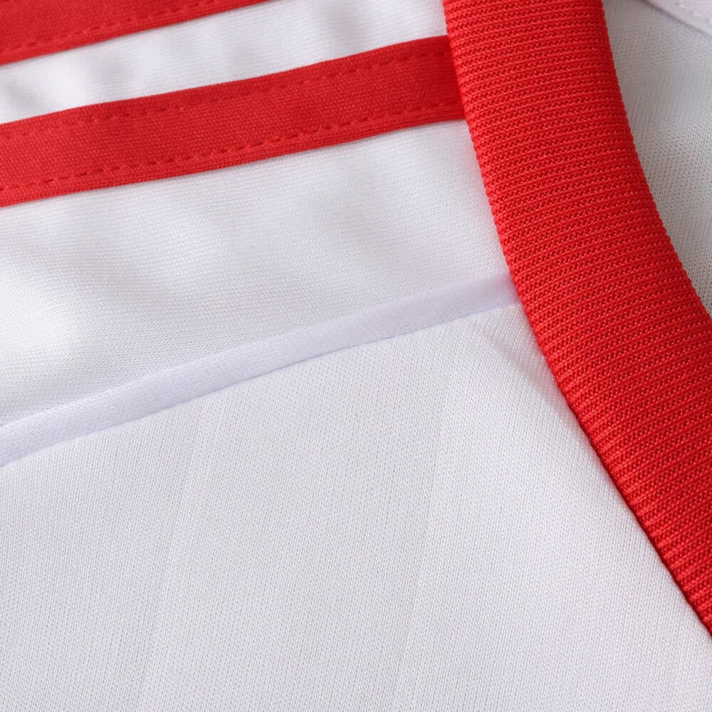 Close-up of Sevilla FC 2025/26 Home Fan Version jersey fabric showing red and white details.