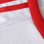 Close-up of Sevilla FC 2025/26 Home Fan Version jersey fabric showing red and white details.
