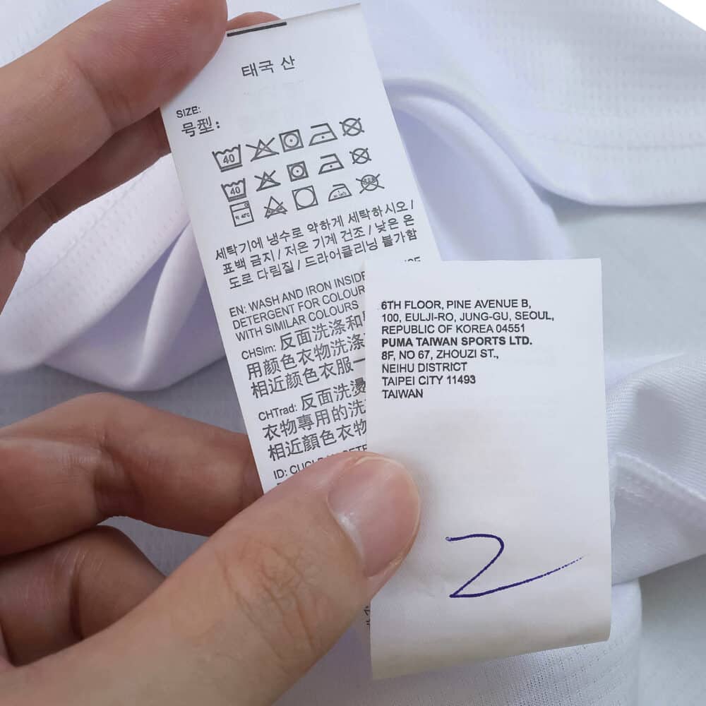 Close-up of care and manufacturer labels on the Valencia Home 2025/26 Fan Version jersey.