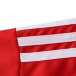 Close-up of the 2025/26 Granada Home Fan Version jersey showing red fabric with three white shoulder stripes.