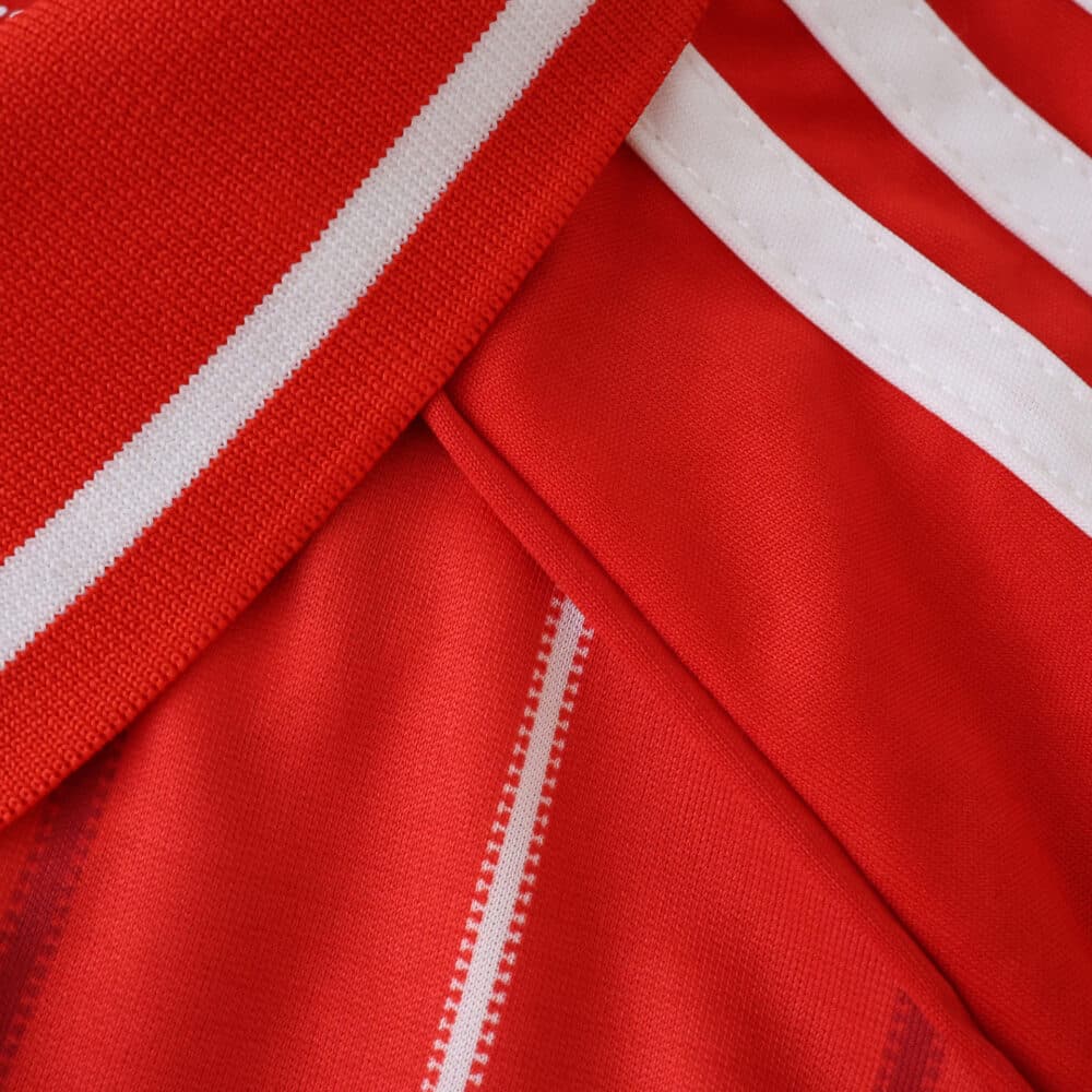 Close-up of the Nottingham Forest 2025/26 home fan jersey showing red fabric with white stripes.