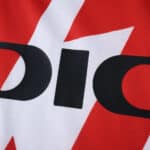 Close-up of Rayo Vallecano 2025/26 home fan jersey featuring red lightning design and sponsor logo.