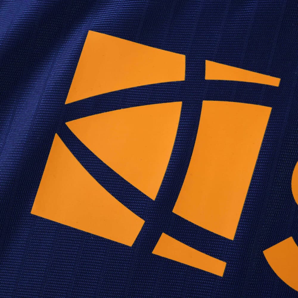 Close-up of the orange sponsor logo on the Newcastle United 2025/26 third player version jersey.