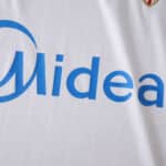 Close-up of Sevilla FC 2025/26 home fan jersey showing sponsor logo "Midea" on white fabric.