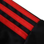 Close-up of Sevilla FC 2025/26 Third Fan jersey showing black fabric with three bold red stripes on the shoulder.